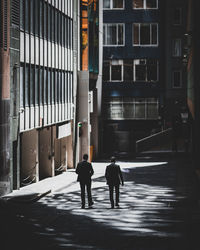 Rear view of people walking on street amidst buildings in city
