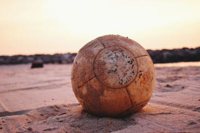 Close-up of ball on sand at beach against sky during sunset