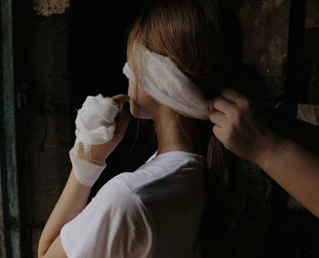 Cropped hand tying bandage on face