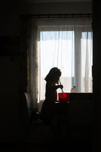 Side view of woman sitting on chair at home