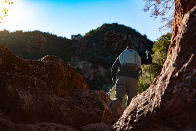 Middle-aged man climbs the mountain in the garraf natural park, supported by hiking poles.