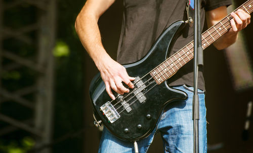 Midsection of man playing guitar at concert