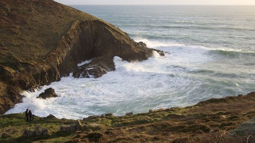 Scenic view of sea waves splashing on shore against sky