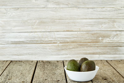 Close-up of avocados in bowl on wooden table