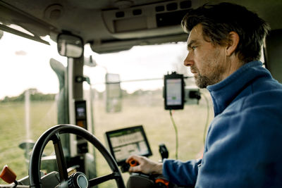 Mature farmer driving tractor on field