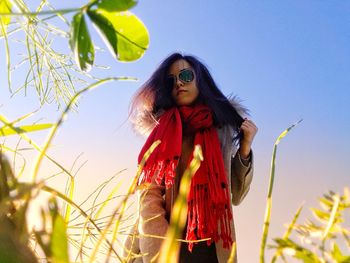 Low angle portrait of woman against blue sky