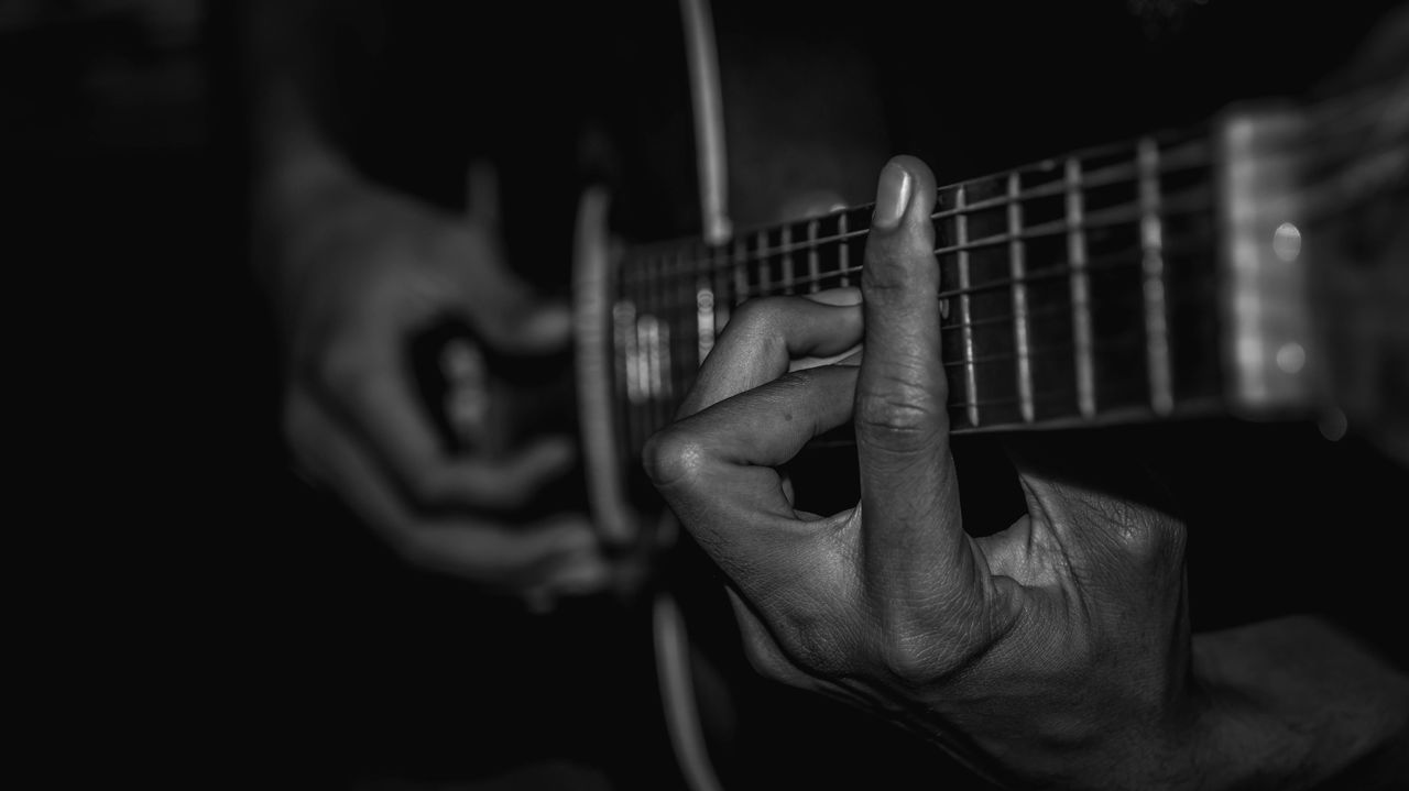 MIDSECTION OF MAN PLAYING GUITAR AT MUSIC CONCERT