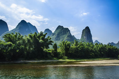 Scenic view of river by trees against sky