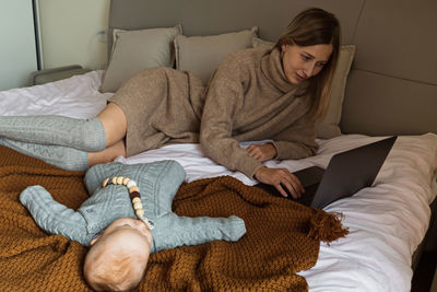 Low section of woman sitting on bed at home