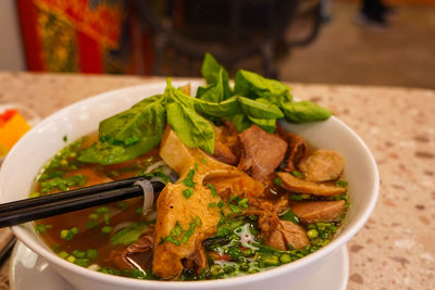 Pho bo or vietnamese soup with beef and meat balls served in a white bowl at the restaurant. 