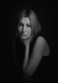 Close-up portrait of young woman against black background