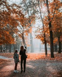 Rear view of women walking on sidewalk during autumn