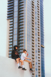 Low angle view of men sitting against building