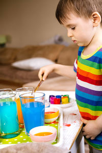 Side view of boy playing with paint at home