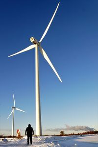 Low angle view of traditional windmill by sea against clear sky