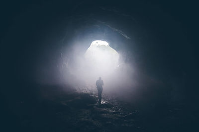 Silhouette person walking in tunnel