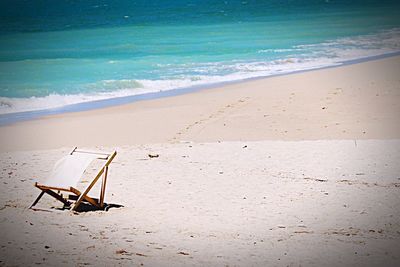 Chairs and table at beach against sky