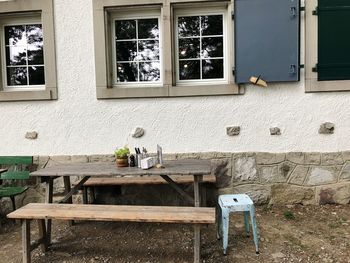 Empty chairs and table by window on wall of building