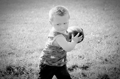 Boy holding umbrella on field