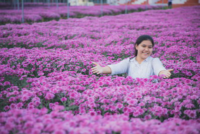 Portrait of woman with purple flowers on field