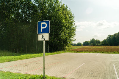 Road sign by trees against sky