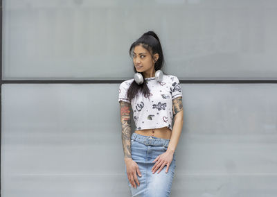 Portrait of young woman standing against wall