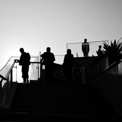 Silhouette people on staircase against clear sky