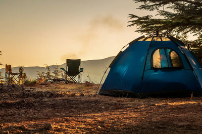 Tent on field against sky during sunset