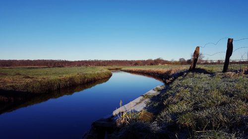 Scenic view of green landscape against clear blue sky
