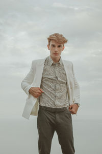 Portrait of young man standing against sky