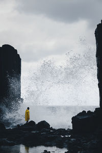 Sea waves splashing on rocks against sky