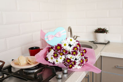 Bouquet of spring flowers on kitchen table with gift box.