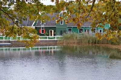 House by lake against trees and building