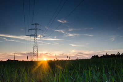 Electricity pylon on field against sky during sunset