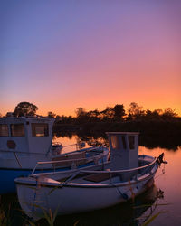 Boat moored in lake against sky during sunset
