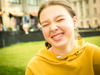 Close-up of girl with closed eyes smiling on field