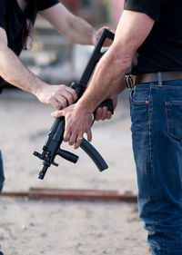 Midsection of men holding gun