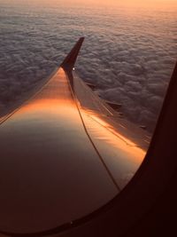 Airplane wing against sky during sunset