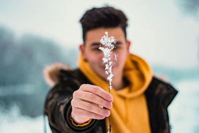 Handsome boy holding a frozen plant, winter portrait, fabulous background