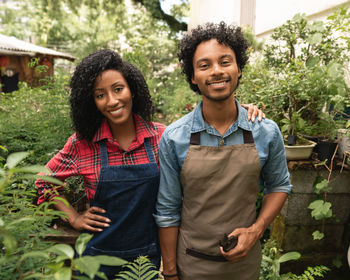 Portrait of happy friends standing against plants