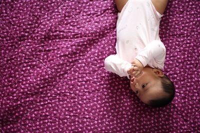 High angle view of cute baby boy lying on purple blanket