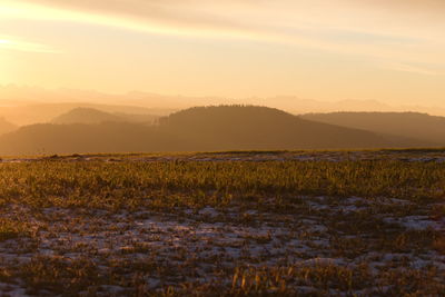 Scenic view of field against sky during sunrise.