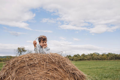 Cute boy sitting on haystack