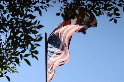 Low angle view of flag waving against clear blue sky