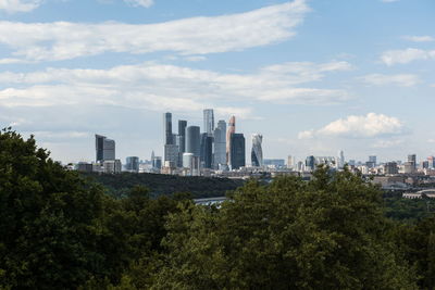 Trees and cityscape against sky