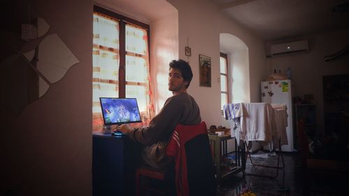 Man looking through window at home