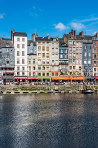 Buildings by river against sky in city