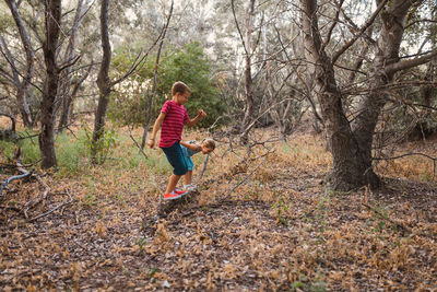 Full length of boy playing in forest