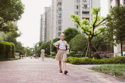 Portrait of woman walking on footpath in city