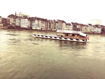 Boats in river by city against clear sky